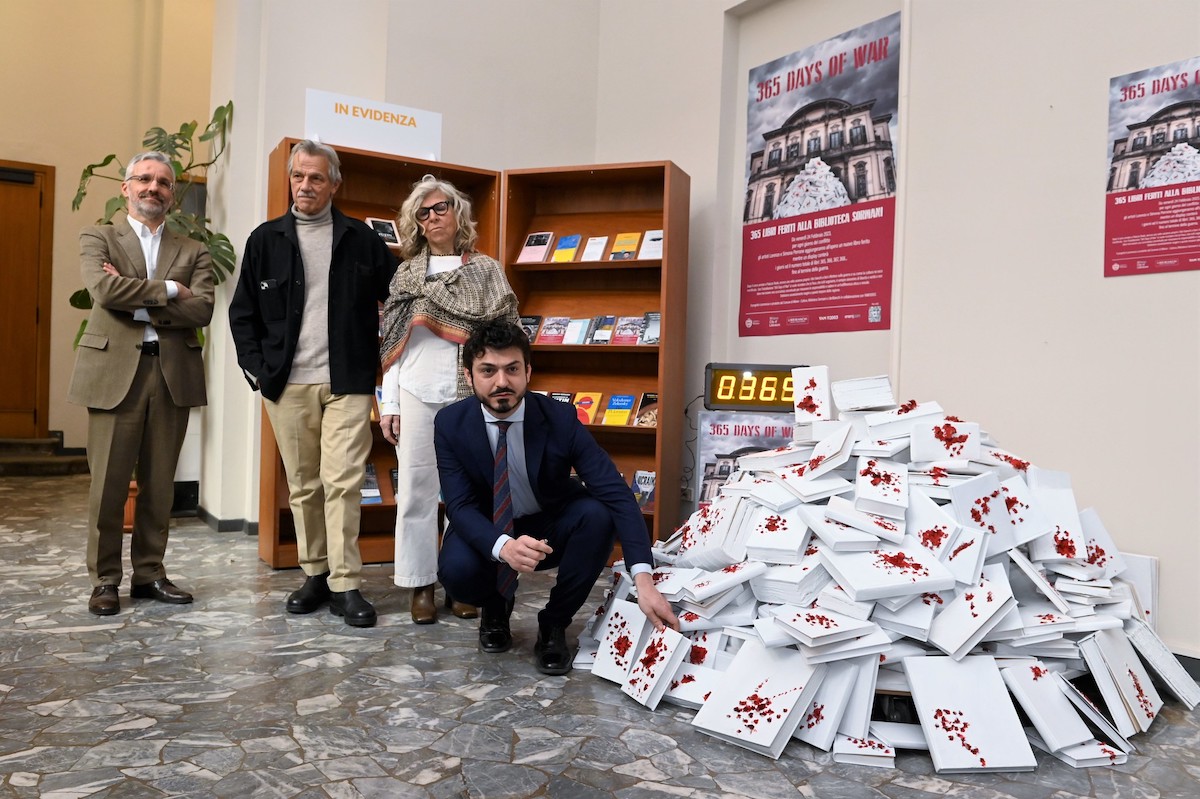 Tommaso Sacchi accroupi devant les livres ensaglantés © Comune di Milano